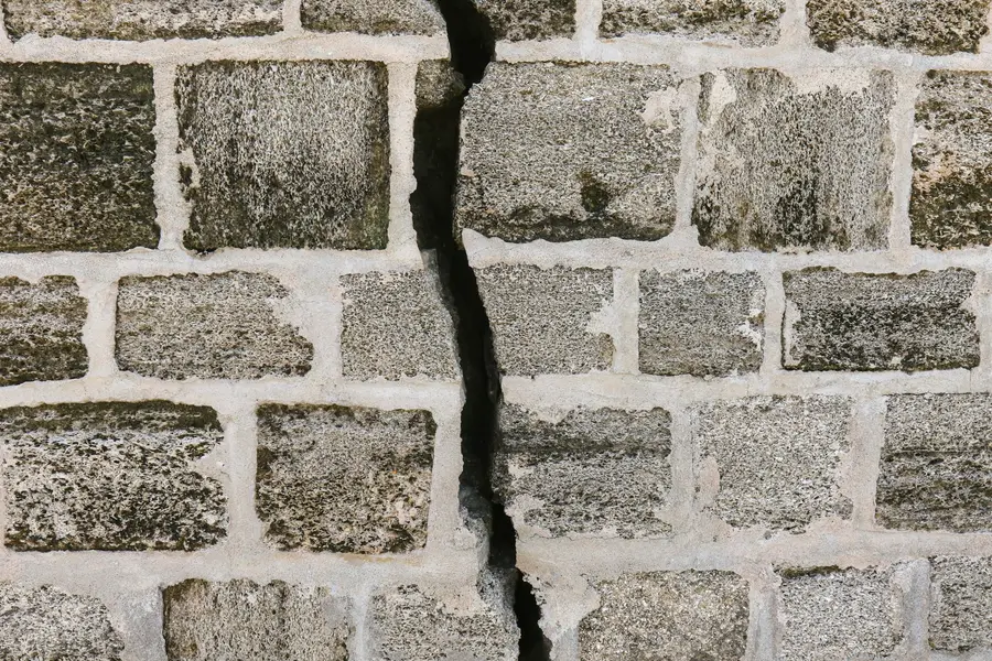 Wide crack running through the mortar joints of a stone block wall