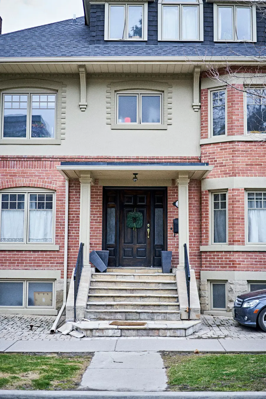 Brick house entrance with stone steps, white columns and a dark front door