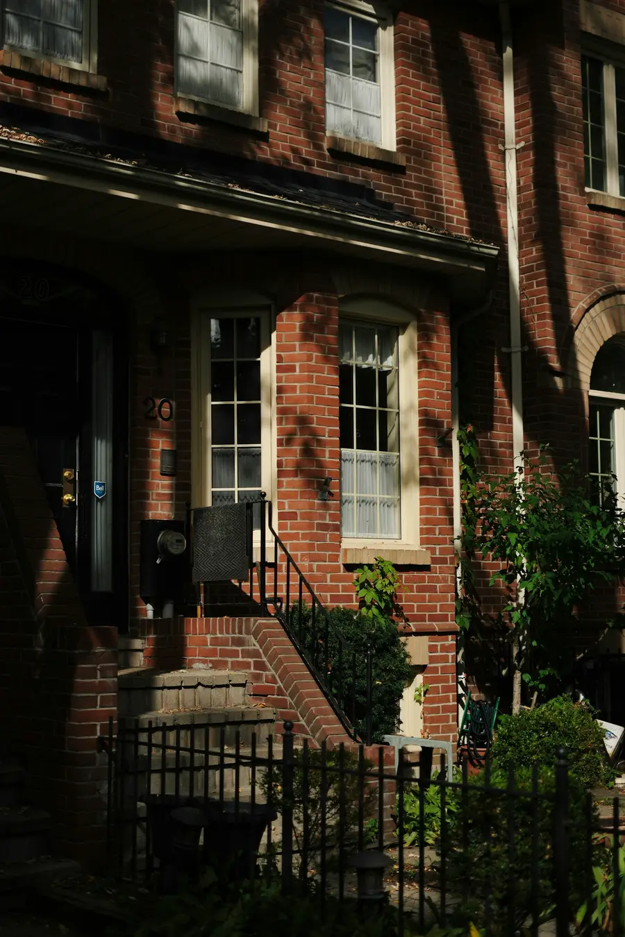Brick house front with steps, an iron railing and a tall window