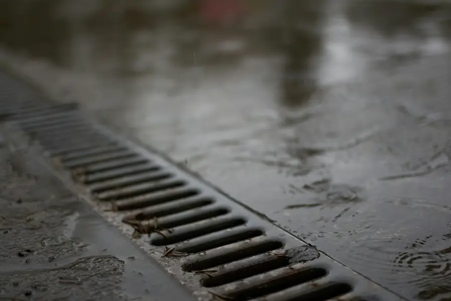 Metal channel drain grate set in wet pavement