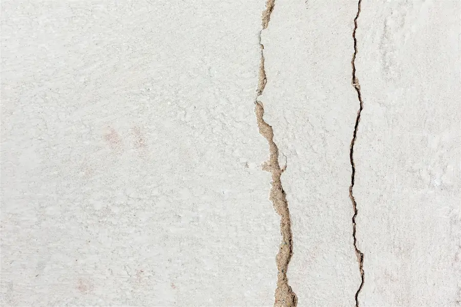 Two parallel vertical cracks in a light painted wall