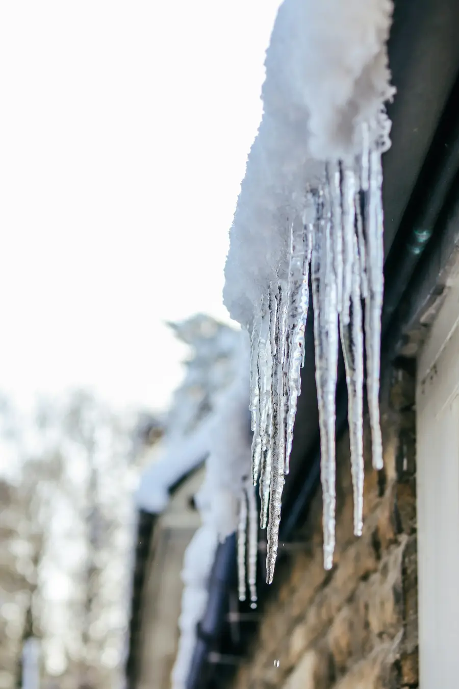 Long icicles hanging from the eave of a house in winter