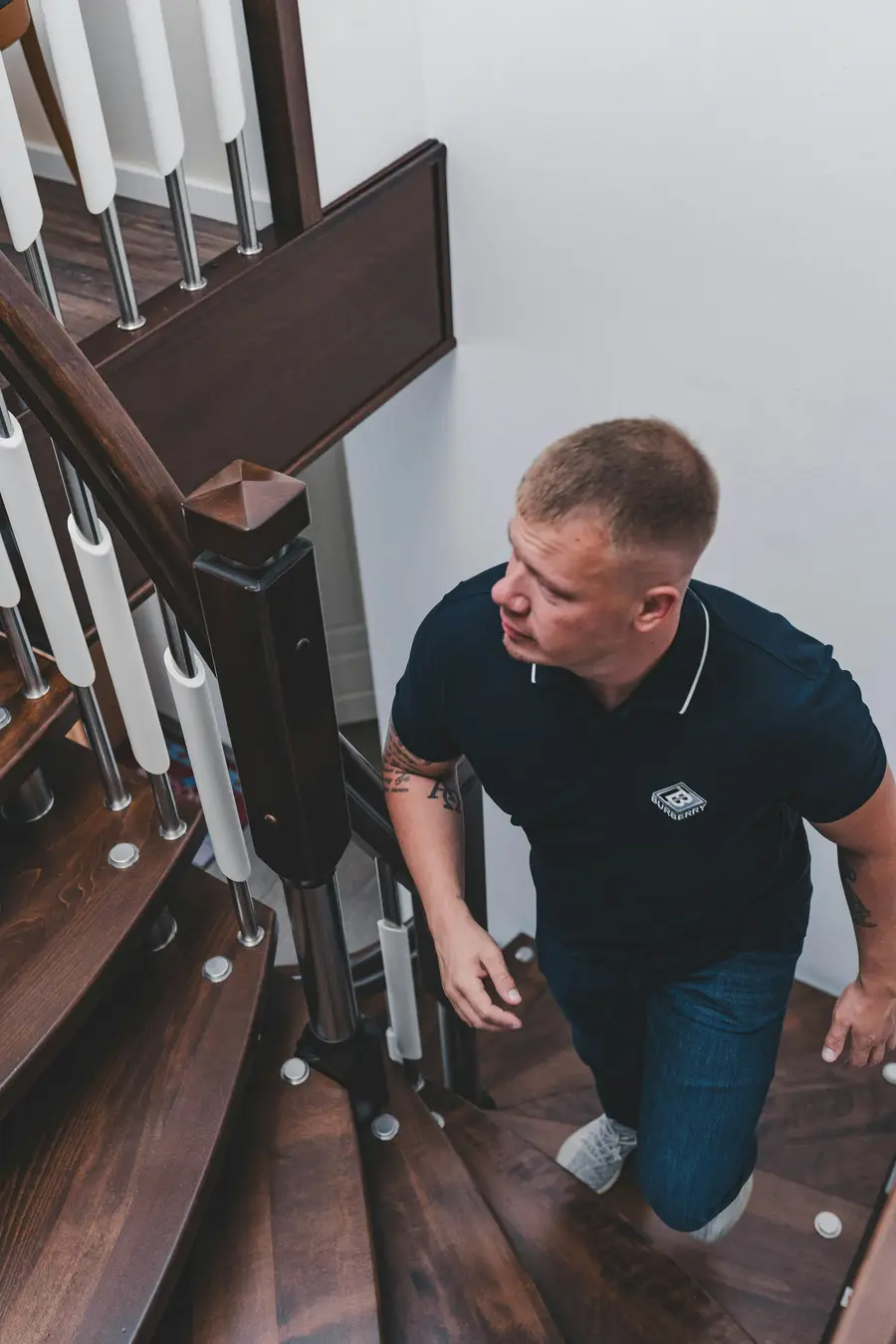 Man crouching on a staircase and looking closely at the wall beside it