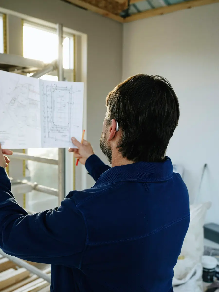 Man holding up a site drawing and checking it with a pencil