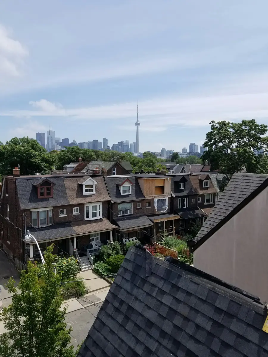 Row of brick houses with dormers and the Toronto skyline behind them